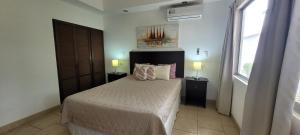 a bedroom with a bed with two lamps and a window at Villas Eco Development in Playa Junquillal