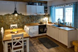 a kitchen with a table and a stone wall at Horský apartmán Vrátna-Saška in Terchová