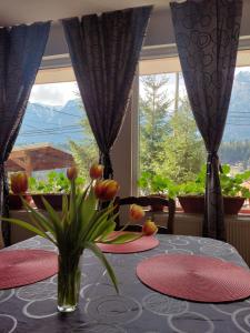 un tavolo con un vaso di fiori su un tavolo con una finestra di Mountain View a Buşteni