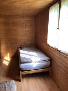 uma pequena cama num quarto de madeira com uma janela em Chata u certovych hlav 3 em Želízy