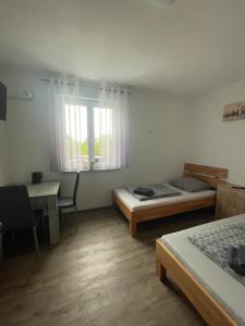 een kamer met 2 bedden, een bureau en een raam bij Lora Appartements in Mainbernheim