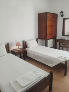 two beds in a room with two tables and a mirror at Paradise in Kefalos +14 photos