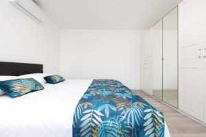 a white bedroom with a large bed with a blue blanket at Apartments Olea in Mali Lošinj
