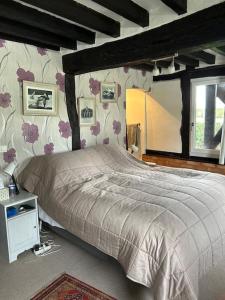 1 dormitorio con 1 cama grande con flores en la pared en Chaumière de charme cosy, en Saint-Éloi-de-Fourques