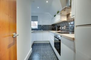 uma cozinha com armários brancos e piso em azulejo preto em Hudson's Haven Apartments by Week2Week em Newcastle upon Tyne