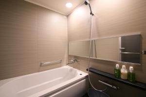 a bathroom with a white bath tub and a mirror at Hotel Gracery Shinjuku in Tokyo
