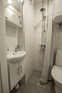uma casa de banho branca com um lavatório e um chuveiro em A Lovely apartment near Railway station and Arena. em Tampere