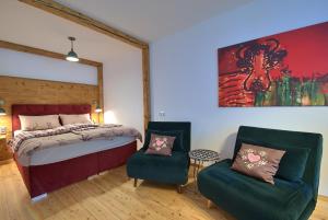 1 Schlafzimmer mit einem Bett und 2 Stühlen in der Unterkunft Alpen Apartment Werfenweng - Ruhe - Pool in Werfenweng