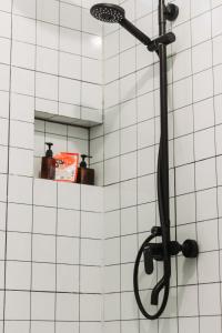 a shower with a black shower head on a white tiled wall at Awana Farmhouse Dieng in Dieng