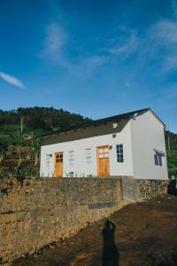 a white house with orange doors on a stone wall at Awana Farmhouse Dieng in Dieng