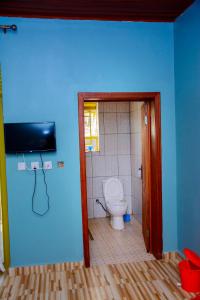 a bathroom with a toilet and a blue wall at IREBERO DREAM HOME in Kayonza