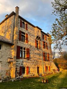 un vieux bâtiment en briques avec des volets rouges dans l'établissement Manoir du Grail, à Devesset