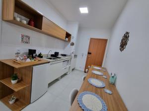 eine Küche mit einem langen Holztisch mit blauen Tellern darauf in der Unterkunft Morada da Fé II à 300 m da canção nova Cond. da Fé in Cachoeira Paulista