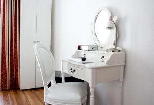 einen weißen Schminktisch mit einem Spiegel und einem Stuhl in der Unterkunft Hotel Weisses Kreuz in Interlaken