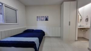 ein Schlafzimmer mit einem blauen Bett und einem Waschbecken in der Unterkunft Morada da Fé II à 300 m da canção nova Cond. da Fé in Cachoeira Paulista