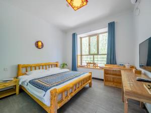 a bedroom with a bed and a desk and a television at Dunhuang Hu Yang Inn in Dunhuang