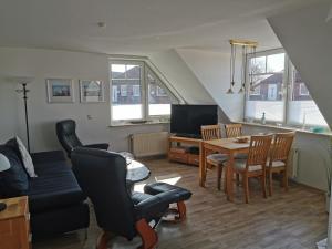 a living room with a couch and a table and chairs at Yachthus in Carolinensiel