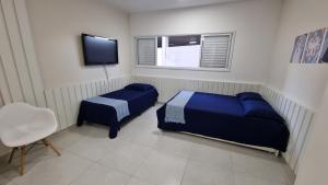 um quarto com 2 camas, uma televisão e uma cadeira em Morada da Fé II à 300 m da canção nova Cond. da Fé em Cachoeira Paulista