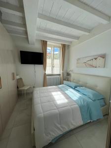 um quarto branco com uma cama e uma televisão em La casa di Angelica em Levanto
