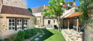 einen Hinterhof eines Hauses mit einem Garten mit einem Baum in der Unterkunft La Maison d'Emilie - Appartements in Chaumes-en-Brie