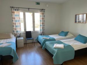 a hotel room with two beds and a chair at Gästhem Neptun in Mariehamn
