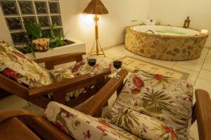 a living room with a tub and a couch and two glasses of wine at Pousada Morada das Nuvens in Monte Verde