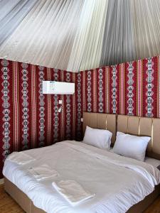 - un lit à baldaquin rouge et blanc dans l'établissement Feras Camp Wadi Rum, à Wadi Rum