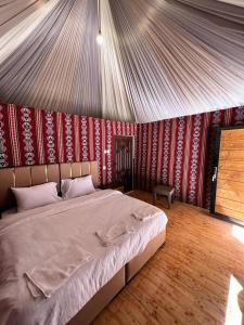 - une chambre avec un grand lit dans une tente dans l'établissement Feras Camp Wadi Rum, à Wadi Rum