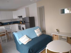 a living room with a blue couch and a kitchen at T2 avec terrasse ensoleillée à 5 min de la plage Pornichet in Pornichet