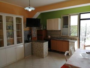 cocina con paredes verdes, armarios blancos y mesa en Appartamento Policastro - Vista mare, 