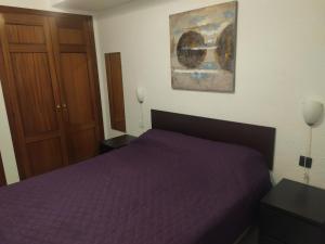 a bedroom with a purple bed and a painting on the wall at El Médano PlayaMar in El Médano