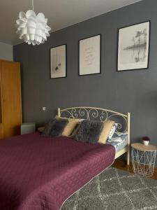 a bedroom with a bed with purple sheets and pictures on the wall at Apartment for a pleasant stay in Odesa