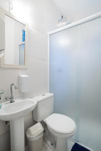 a white bathroom with a toilet and a sink at Aconchego Azul Suítes Vila Mariana in Sao Paulo