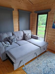 a gray couch in a room with a large window at Desart School Garden Chalet in Kilkenny