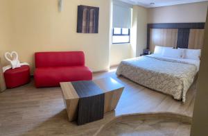 ein Hotelzimmer mit einem Bett und einem roten Stuhl in der Unterkunft HOTEL M ELITE ROJO in Mexiko-Stadt