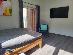 1 dormitorio con 1 cama, TV y silla en Ferienwohnung Bad Doberan - mit Garten und Terrasse - 2023 neu renoviert, en Bad Doberan