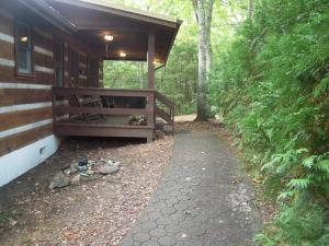 un porche de una cabaña con un banco en el bosque en Bears Hideaway, en Pigeon Forge