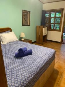 een slaapkamer met een bed met een paarse handdoek erop bij Posada Nena Caribe in Puerto Viejo