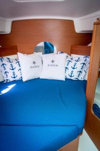 a bed with blue and white pillows on a boat at Private boat with skiper in Prijevor