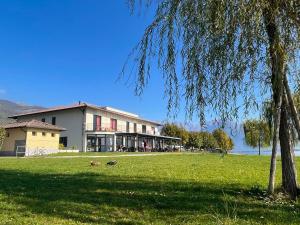 un edificio en un campo con un árbol en el primer plano en Lake Como Beach Hostel, en Domaso