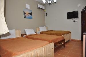 a room with three beds and a flat screen tv at Dahab Plaza Hotel in Dahab