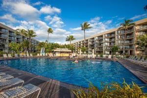 una piscina en un complejo con sillas y palmeras en Maui Sunset B217 condo, en Kihei