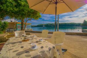 a table with chairs and an umbrella and water at Holiday house Punta Blue & Orange 5m from the sea, island Cres in Punta Križa