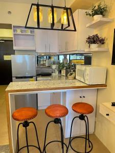 une cuisine avec deux tabourets à un comptoir et un four micro-ondes dans l'établissement AVIDA ATRIA Tower 3, à Iloilo