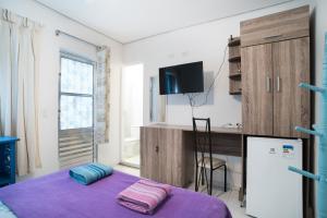 a small room with a bed and a desk at Aconchego Azul Suítes Vila Mariana in Sao Paulo