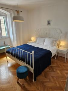 een slaapkamer met een bed met een blauwe deken en een stoel bij Our Best Chapter in Split