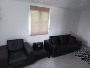sala de estar con sofá negro y silla en Your Space, en Donji Stoliv