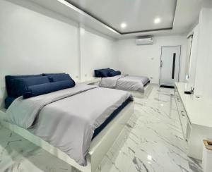 Cette chambre comprend 2 lits dans une chambre dotée de murs blancs et de sols en marbre. dans l'établissement Family Cliff House - private jacuzzi with beach views, à Pathiu