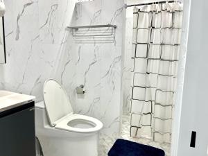 La salle de bains blanche est pourvue d'une douche et de toilettes. dans l'établissement Family Cliff House - private jacuzzi with beach views, à Pathiu