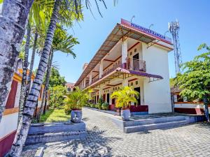 a building with palm trees in front of it at SPOT ON 92527 Penginapan Kangean Syariah in Sumenep